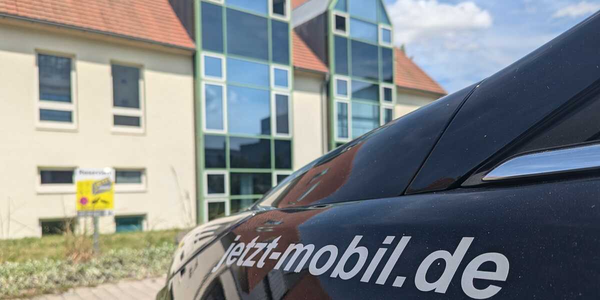 Kotflügel eines Autos vor einem Haus mit der Website jetzt-mobil.de